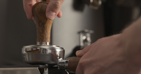 man tamping freshly ground coffee in portafilter