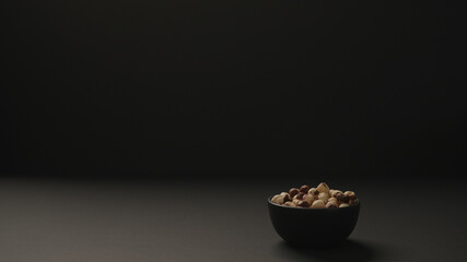 roasted hazelnuts in black bowl on black paper background