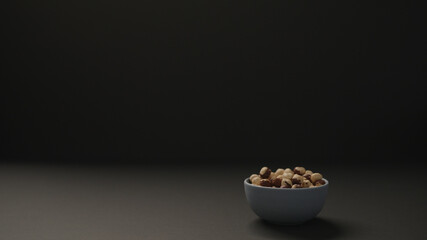 roasted hazelnuts in blue bowl on black paper background