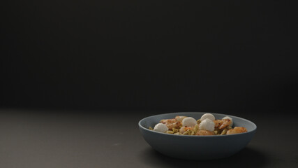pesto penne with fried shrimps and mozzarella in blue bowl on black background