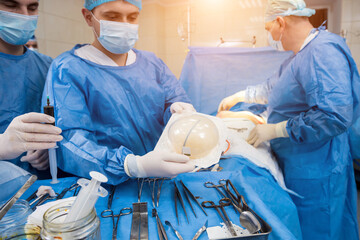Surgeon in operation room is holding sterile breast silicone implant in hands.