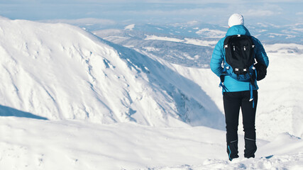 Back view of a Mountaineer wearing backpack. Snow-covered landscape - Cloudy Blue Sky. High quality photo