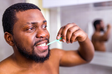 african american man cleaning his teeth with floss