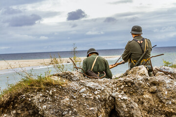 Historical reenactment. German soldiers during the Second World War. Wehrmacht soldiers patrol the  coast. View from the back.   