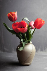 red tulips in a vase on a gray background