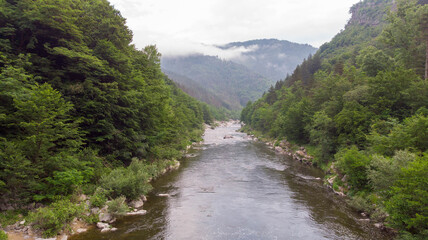Fototapeta na wymiar River stream on a green valley in an amazing and peaceful national park with fog and cloudy. Rural scenery mount and canyon in the balkan