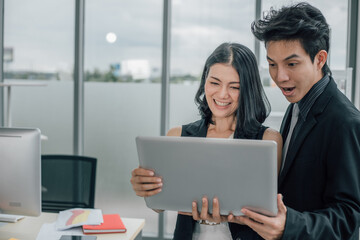 Young male and female using laptop and looking at camera.