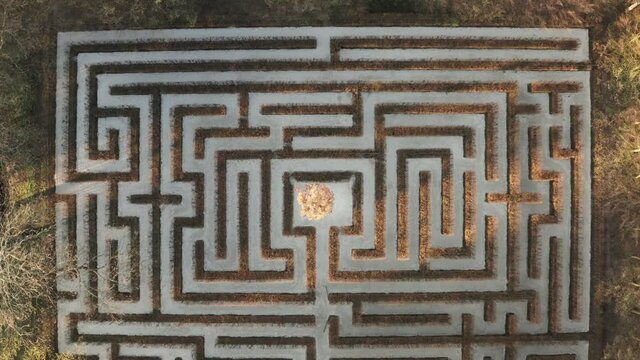 Geometrical background, top down view of a symmetrical labirynth. Aerial shot of a green maze, path and challenge concept.