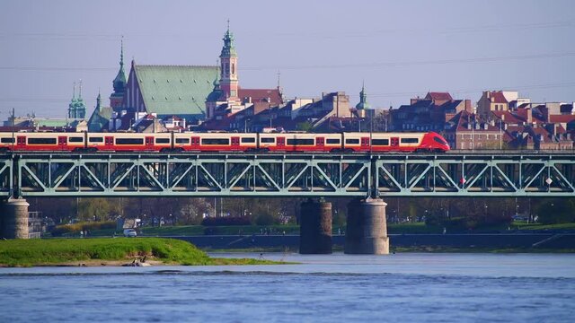 Panorama Warszawy w słoneczny dzień znad Wisły z okolic Żerania. Pociąg na moście kolejowym