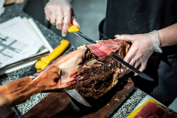 butcher with a knife cuts the jamon