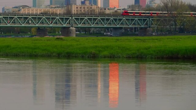 Panorama Warszawy w słoneczny dzień znad Wisły z okolic Żerania. Pociąg osobowy na moście kolejowym nad Wisłą przy stacji Warszawa ZOO