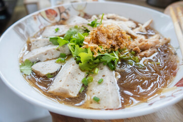 Boiled vermicelli with white pork sausage with vegetables; sprinkle in a bowl with chopsticks