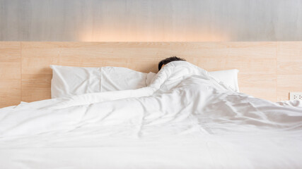Fototapeta na wymiar Man sleeping on the bed in white blanket at lately morning