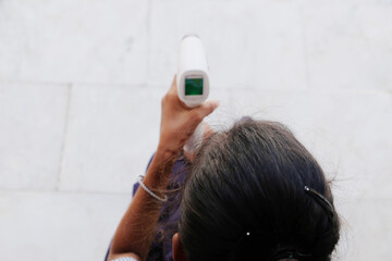 High angle shot of a young Indian girl using an electronic thermometer