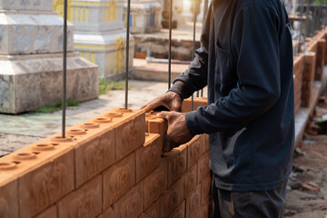 Builder carefully puts red brick on the masonry. Quick work bricklayer. Guy measures level masonry. Man is building brick wall. Correctly calculate material. Builder manually carries brick structure
