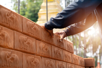 Builder carefully puts red brick on the masonry. Quick work bricklayer. Guy measures level masonry. Man is building brick wall. Correctly calculate material. Builder manually carries brick structure