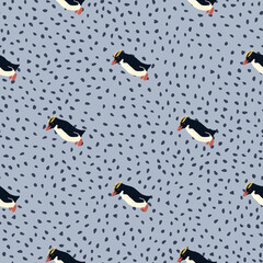 Decorative arctic animals seamless pattern with crested penguins shapes. Blue dotted background. Cartoon print.