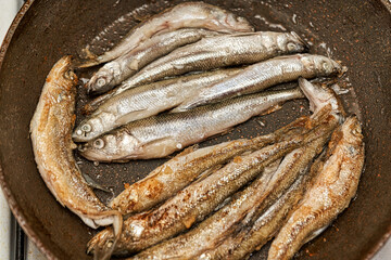 Crispy breaded European smelt in a black skillet.