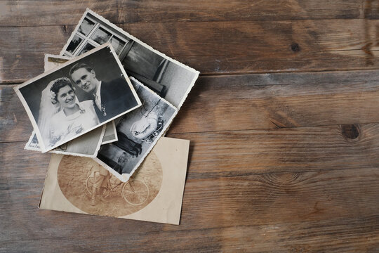 stack of old vintage monochrome photographs on photographic paper on natural wood background, concept of genealogy, memory of ancestors, family tree, nostalgia, childhood, remembering