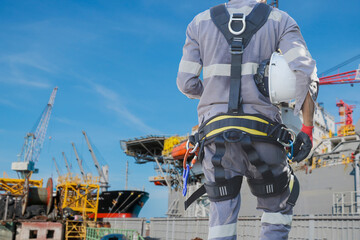 Workers wearing safety harness and safety line working in shipyard work at building oil rig drilling plant background for safety concepts of residential building under construction.