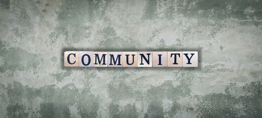 Community - word from wooden blocks with letters, group of people community concept, random letters around, top view on cement wall background
