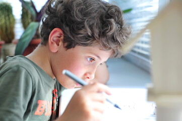 Cute little boy is doing homework. Distance learning during a pandemic.
