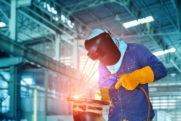 welder in Industrial worker with welding tool with sparks light weld and smokes in factory.