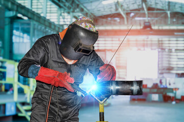 Industrial worker welding metal piping using Tig torch gas inert welder and wearing equipment protection mask in shipyard