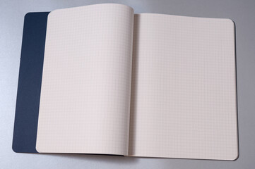 Aufgeschlagenes leeres Notizbuch mit blauem Einband auf silberfarbenen Hintergrund. Großes Textfeld