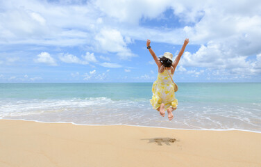 Fototapeta na wymiar Excited energetic happy tourist girl is jumping at the beach on summer vacations, fun and freedom