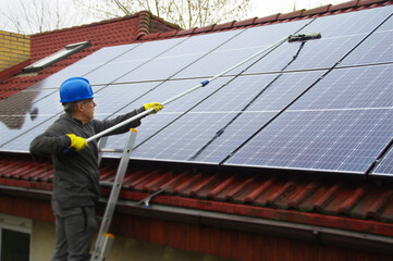 A man on a ladder cleaning solar panels