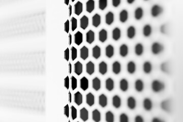 Vertical ventilation grille. Round holes. Metal construction. Dark background. Close-up view. Black and white tones.