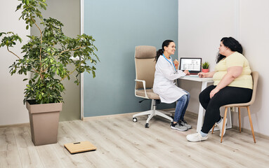 Nutritionist consultation. Dietitian plans a meal plan for a female overweight patient at a diet clinic - obrazy, fototapety, plakaty