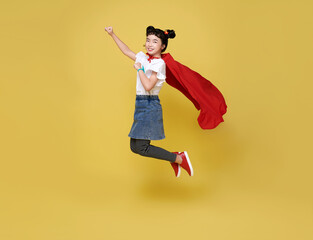Fototapeta na wymiar Little child asian girl plays superhero on yellow background studio shot. Girl power hero concept.