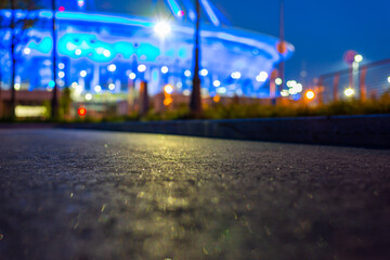 Illumination on the building. Pedestrian sidewalk. Alley with trees and lanterns. Close up view from curb stone level.