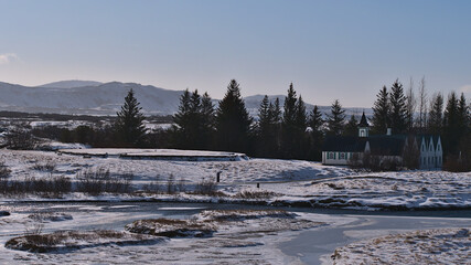 View of historic assembly site of the Icelandic Alþingi parliament in Þingvellir national park, part of Golden Circle, Iceland, with old wooden church Þingvallakirkja in winter season.