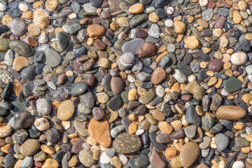 Beautiful texture of colorful smooth stones is on the beach by sea