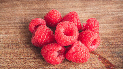 Sweet and delicious raspberry glowing in bright pink and red in a great closeup shot. The tiny strains of hair is clearly visible on the raspberry. Foraging and wild berries concept.
