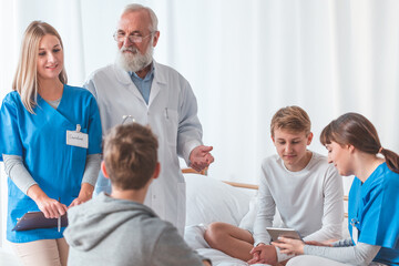 Obraz premium Senior male doctor with patient and female intern at the hospital