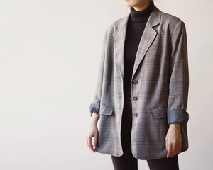 Woman wearing stylish outfit with black turtleneck, grey oversized blazer and black jeans isolated...