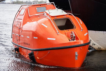 Totally Enclosed Lifeboat floating near big vessel