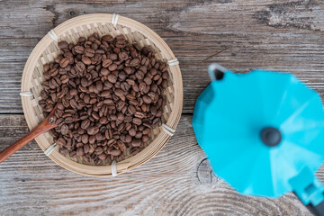 blue geyser coffee maker and roasted coffee beans on the background of an old wooden board