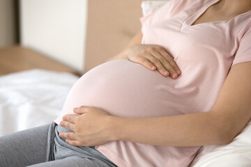 Crop close up of young Caucasian pregnant woman relax at home touch hold baby bump excited to meet kid child. Female resting enjoy easy healthy pregnancy time maternity leave. Motherhood concept.