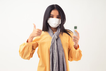 Young Asian woman with tan skin wearing facial mask for Covid-19 protection, holding infrared...