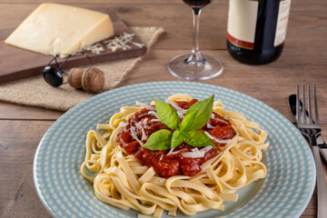 dish with noodles topped with tomato sauce, with a glass of sparkling red wine