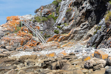 A rocky beach hiking trail with a wooden stairs in the background