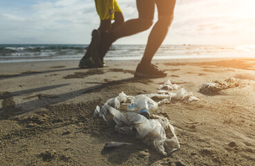 Plastic garbage and people legs on the beach.