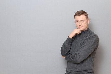 Portrait of serious man propping head with one hand, touching chin