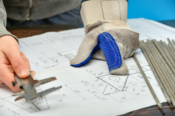 A young welder examines an assembly drawing before work. - Powered by Adobe