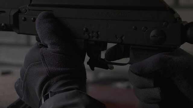 A gloved shooter fires a rifle. Hands close-up. Sniper at firing position